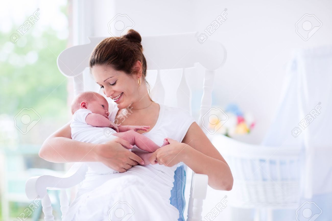 45240711 young mother holding her newborn child mom nursing baby woman and new born boy relax in a white bedr